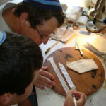 A boy participates in the Sofer Scribe Workshop helping to make his own Tefillin with Rabbi Steve Bar Yakov Gindi