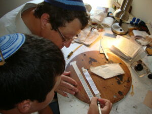 A boy participates in the Sofer Scribe Workshop helping to make his own Tefillin with Rabbi Steve Bar Yakov Gindi